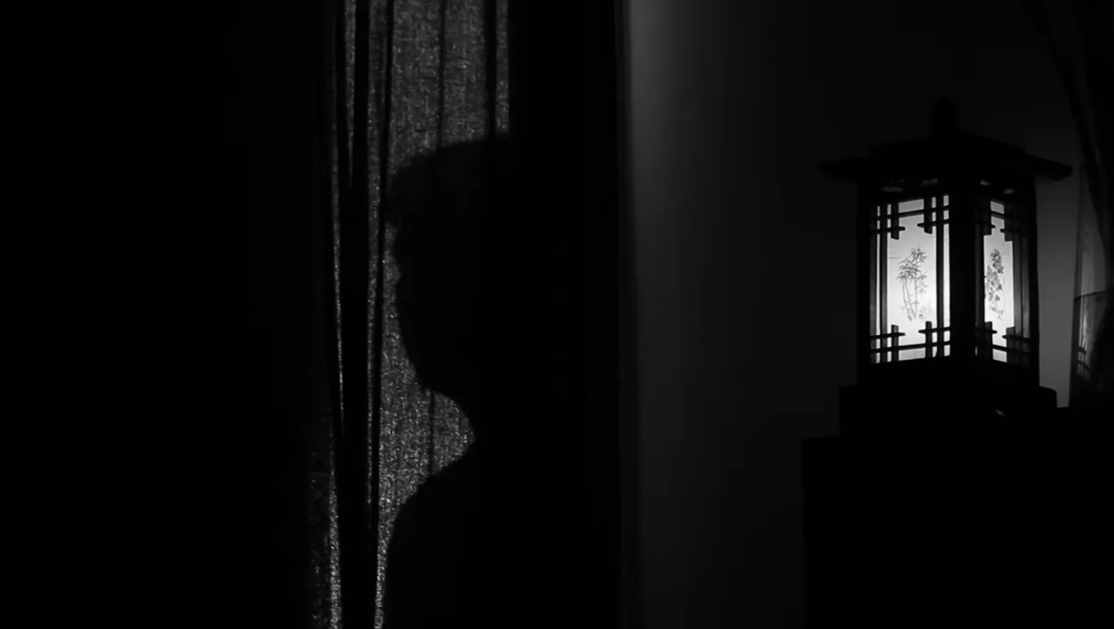 Silueta de Lowlove junto a una lámpara en penumbra